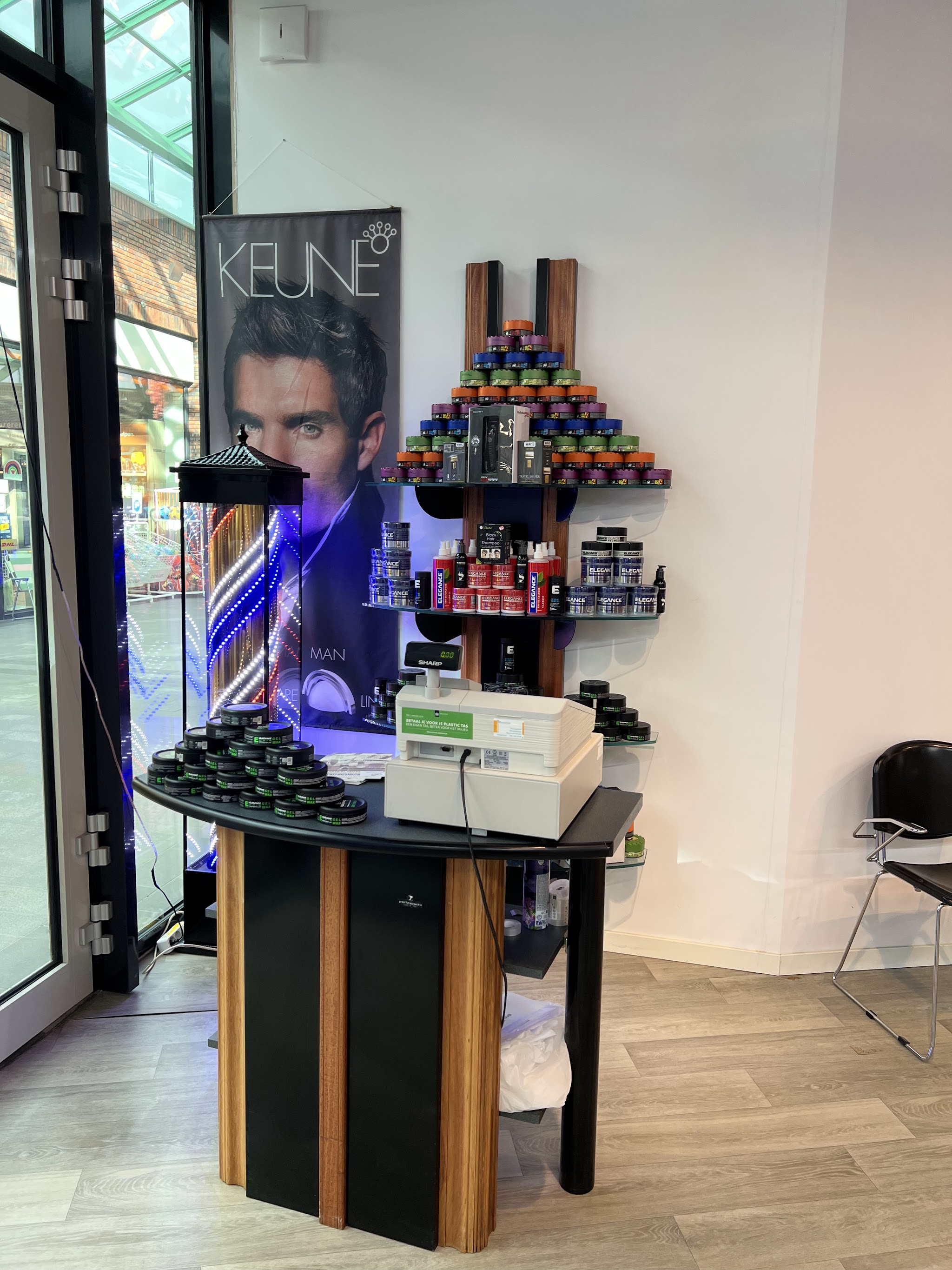 De toonbank van Royal Scissors met het productrek van Keune en Elegance
