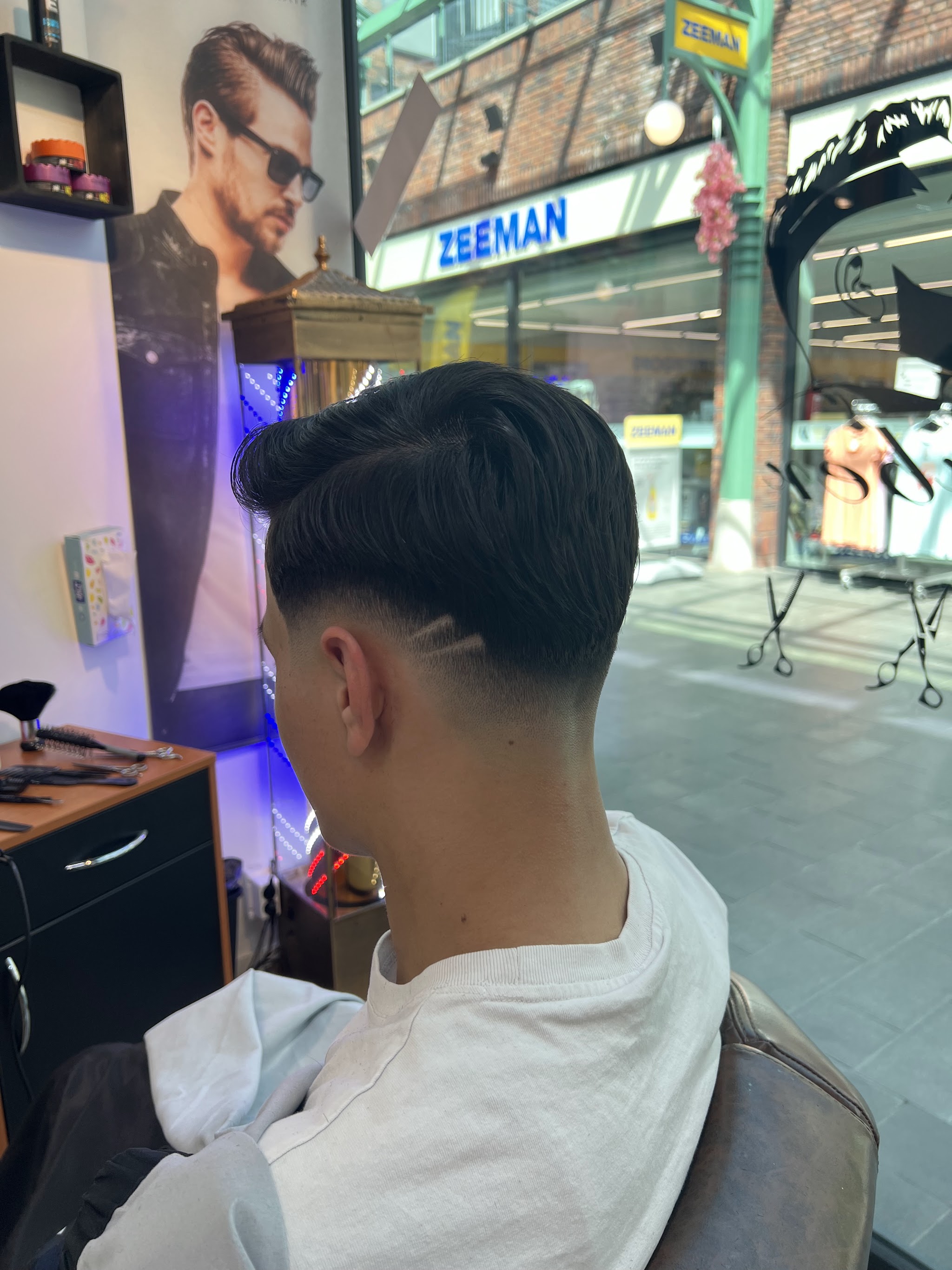 Een getextureerde quiff met een strakke scheiding en een fade aan de zijkant